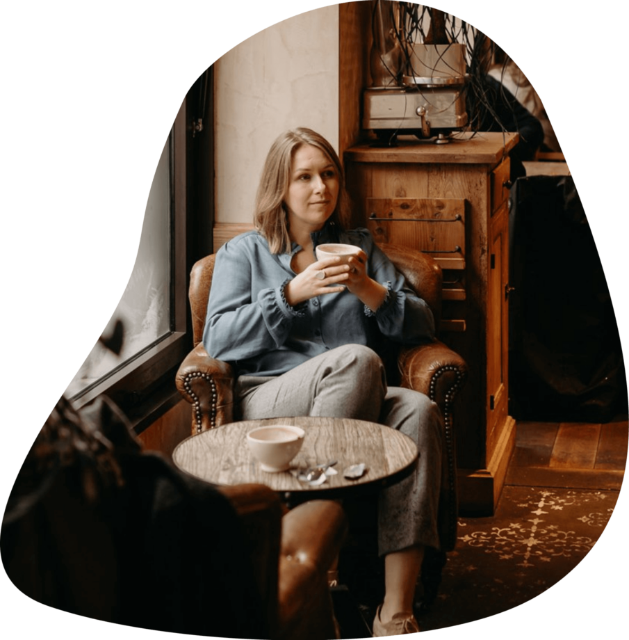 Екатерина в кафе, в кресле, с чашкой кофе в руках